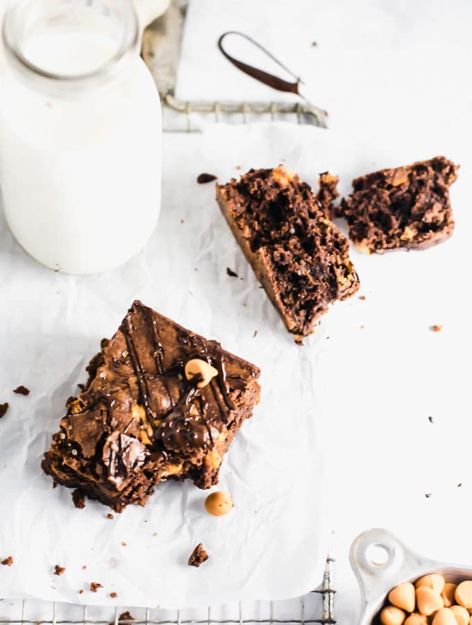 A brownie with a bite taken out of it with a jug of milk in the background